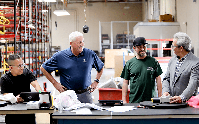 Aero-Zone founder Alfredo Dreyfus chats with employees in Aero-Zone warehouse.