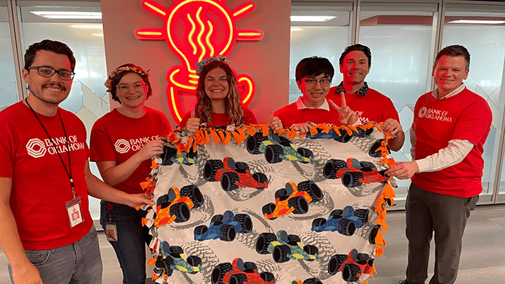 Bank of Oklahoma volunteers holding blankets they made.