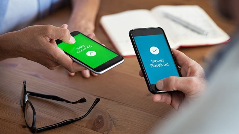 Two people holding phones transferring money from their devices to each other.