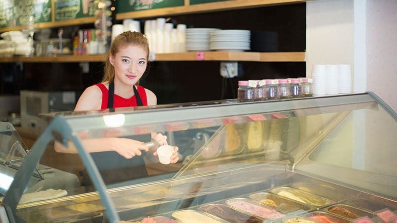 High schooler working at ice cream parlor and learning the power of saving and investing with their first job.