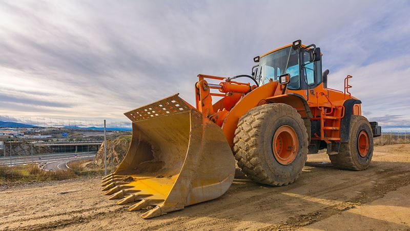 Orange bulldozer moving dirt on a construction site.